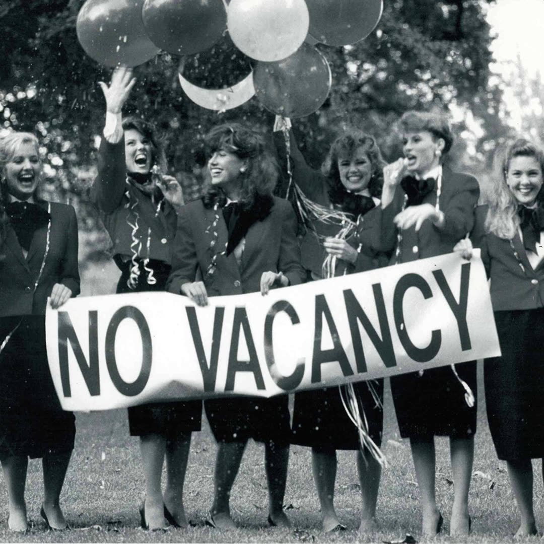 CLASS leasing specialists in the signature red jackets, holding a NO VACANCY banner outside a community in the 1980s